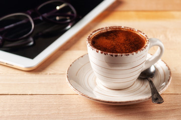 Digital tablet and coffee cup on wooden table