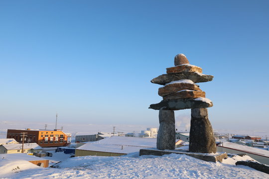 Single Inuksuk or Inukshuk landmark covered in snow on the top of the hill in the community of Rankin Inlet, Nunavut, Canada