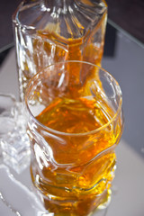 Glass and bottle of whiskey on the mirror surface.