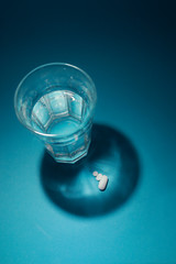 foto vertical de vaso de agua con sombras proyectadas y fármacos