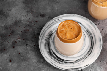 Popular drink Korean dargon coffee made of instant coffee, sugar, hot water and milk in glass on grey background. Cope space