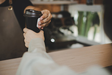 Fototapeta na wymiar young happy handsome man barista serving hot coffee cup to friendly female customer over counter in modern cafe coffee shop, cafe restaurant, service mind, small business owner, food and drink concept
