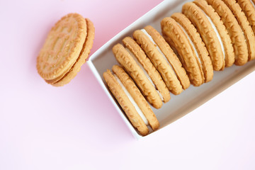 Fototapeta na wymiar round homemade cookies stacked in a stack in a white box with vanilla cream on a light pink background.