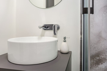 water tap sink with faucet in expensive loft bathroom. detail of a corner shower cabin with wall mount shower attachment