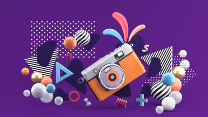 Orange camera surrounded by graphics and colorful balls on a purple background.-3d rendering..