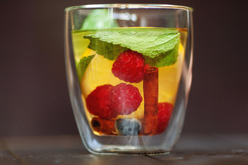 fruit tea in a transparent cup with raspberries lemon mint and cinnamon