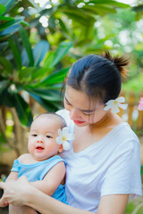 Happy woman and child in the blooming spring garden.baby with his mother enjoying a home outdoors. Mothers day holiday concept