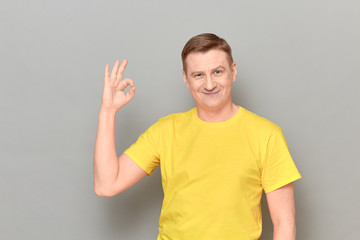 Portrait of happy cheerful mature man showing okay gesture and smiling