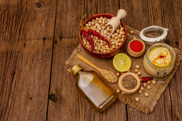 Hummus on old wooden boards background. Dry chickpea, olive oil, lemon, cumin and chili pepper
