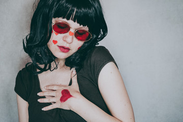 Cool portrait of a young woman wearing red glasses and full of red hearts