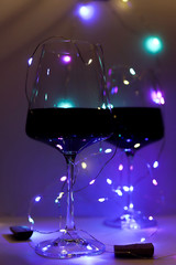 two glasses of red wine against a background of blue and purple lighting