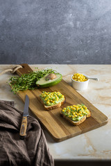 Sandwiches with corn and avocado sauce from bread toasts. Two slices of delicious snacks sprinkled...