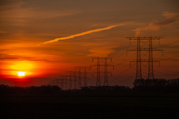 Fototapeta na wymiar Sunset with power pylons in the skyline and trees background