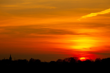 Bright yellow light of the sunset with a village and trees