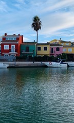 Fototapeta na wymiar colorful houses with palm trees and blue sky and yachts