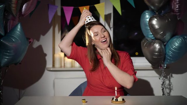 Young woman celebrating her birthday alone. Happy girl bday with cake balloons