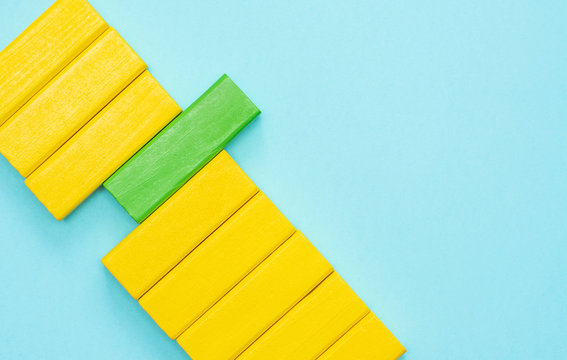 Yellow and green block of jenga block on blue background. Out of the box thinking, Be different concept, Business concept. 