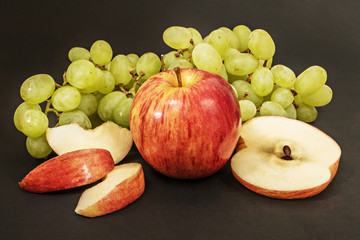 Ripe juicy apples with grapes on a black background
