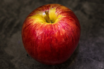 Juicy fresh red apple with water droplets on a dark background with space for text.