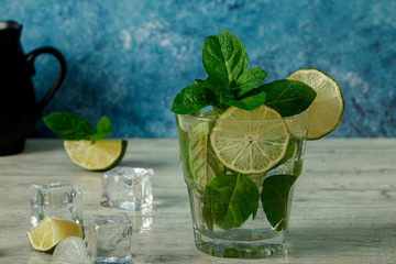 Mojito cocktail with lime, ice cubes and mint in  glass on a black background.Copy space. Mojito cocktail  on a rustic table. Mojito  on a grey stone background.