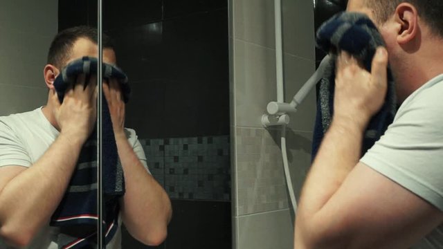 Caucasian man anxiously checks vitiligo spots around his eyes after washing his face. With summer approaching, vitiligo spots become more visible on pale skin as unaffected areas acquire a tan. 