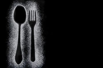 Fork and spoon silhouette made with flour on black background, up horizontal view with free space