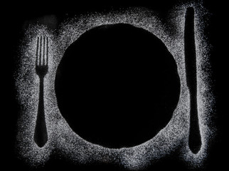Fork, knife and round plate silhouette made with flour on black background, up horizontal view