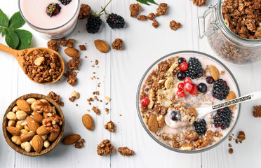 Granola crispy honey muesli with natural yogurt, berries, chocolate and nuts in a bowl against a light background, view from above, horizontal format