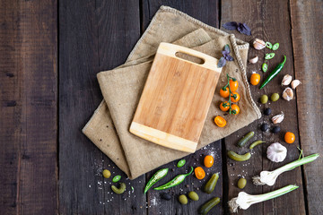 delicious ingredients and empty wooden cutting board for healthy vegetarian cooking, vegan food concept. Top view. Copy space.