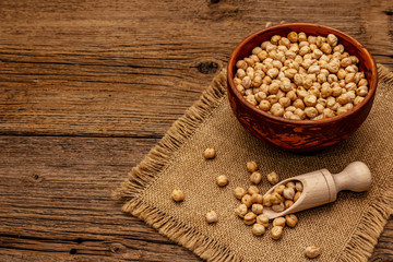 Dry chickpea in ceramic bowl on old wooden boards background. Traditional ingredient for cooking hummus