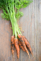 Fresh organic garden carrots on a wooden table, top view