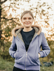 one girl with blond hair tailed in the street dressed in a blue hoody sweatshirt smiling