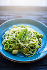Green Pasta with scallop and sauce on blue plate