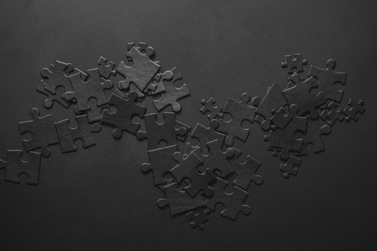 small and large black puzzles randomly scattered on a dark background with space for your text