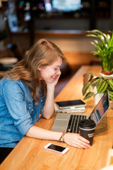 Side view happy woman with coffee watching laptop