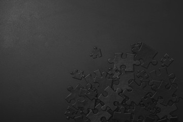 small and large black puzzles randomly scattered on a dark background with space for your text