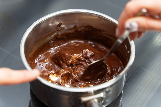 Woman melting chocolate in a pan and mix it with butter