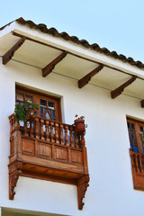 Fachada blanca con balc&oacute;n de madera 