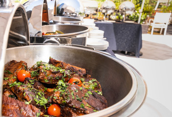 Live food stations in the line. Buffet Table with Row of Food Service Steam Pans, grilled meat and...