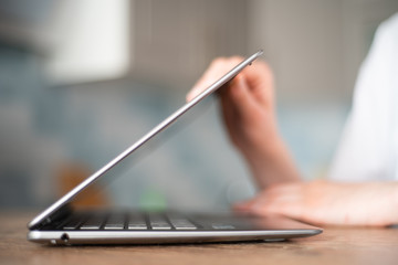 Women's hands open the laptop and lift its lid to start working at home close-up. Remote learning at home via a laptop webcam