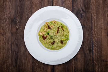 Italian risotto with prawns and zucchini in a white plate on a wooden table.