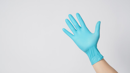 right hand wearing blue latex gloves on white background.