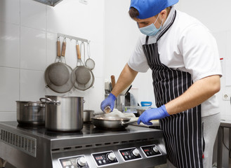 Man in protective mask and gloves frying tasty food