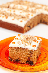 Slice of cake with white cream, caramel spots and nuts on white background