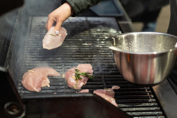Woman putting pieces of turkey with rosemary onto a grill pan