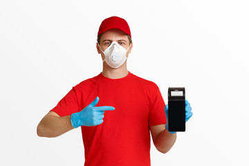 Fototapeta na wymiar Courier in red uniform, protective mask and glove, points finger at contactless terminal.