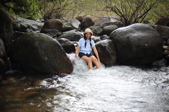 Woman sitting on a rock at Trok Nong Waterfall in Chanthaburi, Thailand