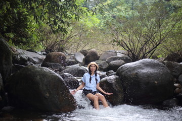 Woman sitting on a rock at Trok Nong Waterfall in Chanthaburi, Thailand