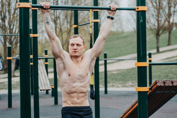 Fitness man with perfect body doing abdominal exercises in the Gym. Fitness toes to bar man pull-ups bars workout exercise at gym