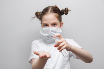 Little girl in a protective medical mask holds a disinfectant, antiseptic, hands, white background. Concept of a virus, coronavirus